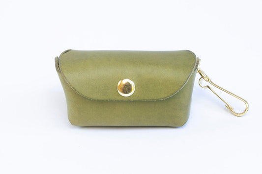 Front-facing Olive Green leather poop bag holder with pop stud closure, brass clip for attaching and bottom dispensing hole for bags, made by Cotswold Hipster