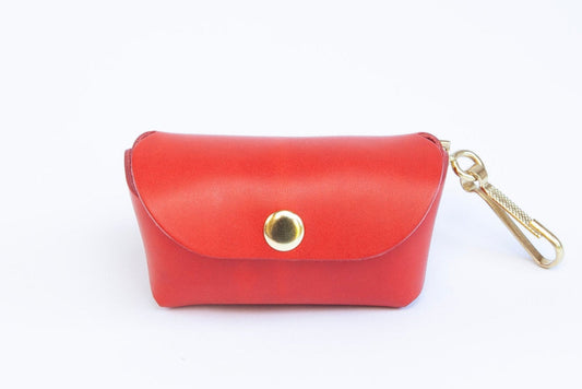 Front view of Poppy Red leather poop bag holder with pop stud closure, bottom dispensing hole, and brass clip for attaching, made by Cotswold Hipster