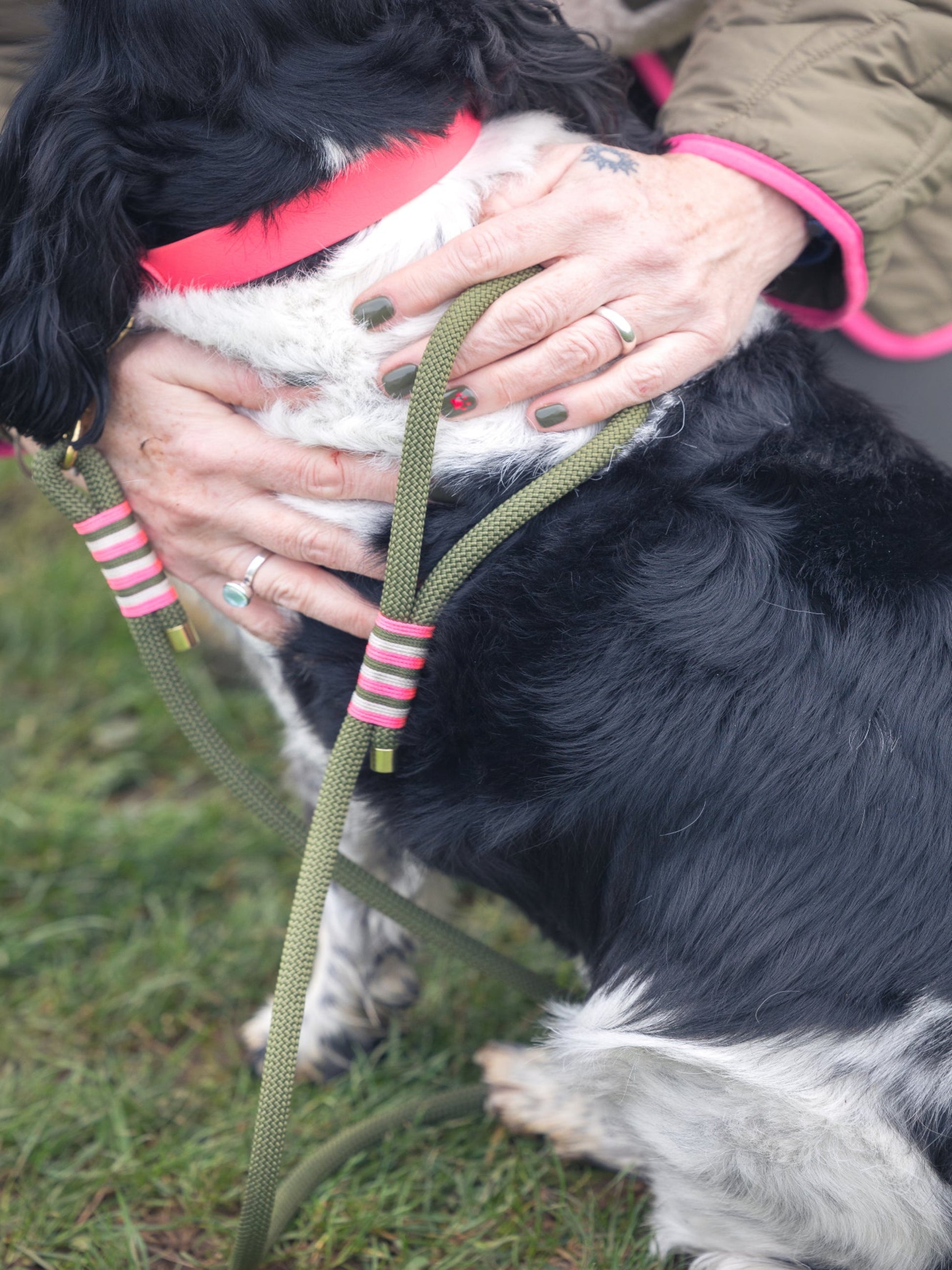 Person holding their dog wearing a BE SEEN! Neon Pink BioThane® collar and matching Neon Pink rope lead, high-visibility coordinated winter dog gear.