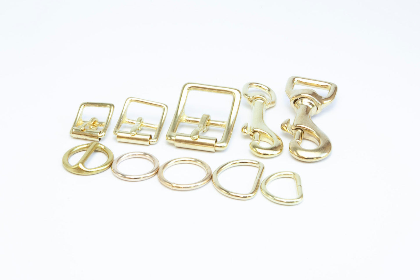 Flatlay of solid brass hardware from the Olive & Raspberry handmade leather dog collar, made by Cotswold Hipster
