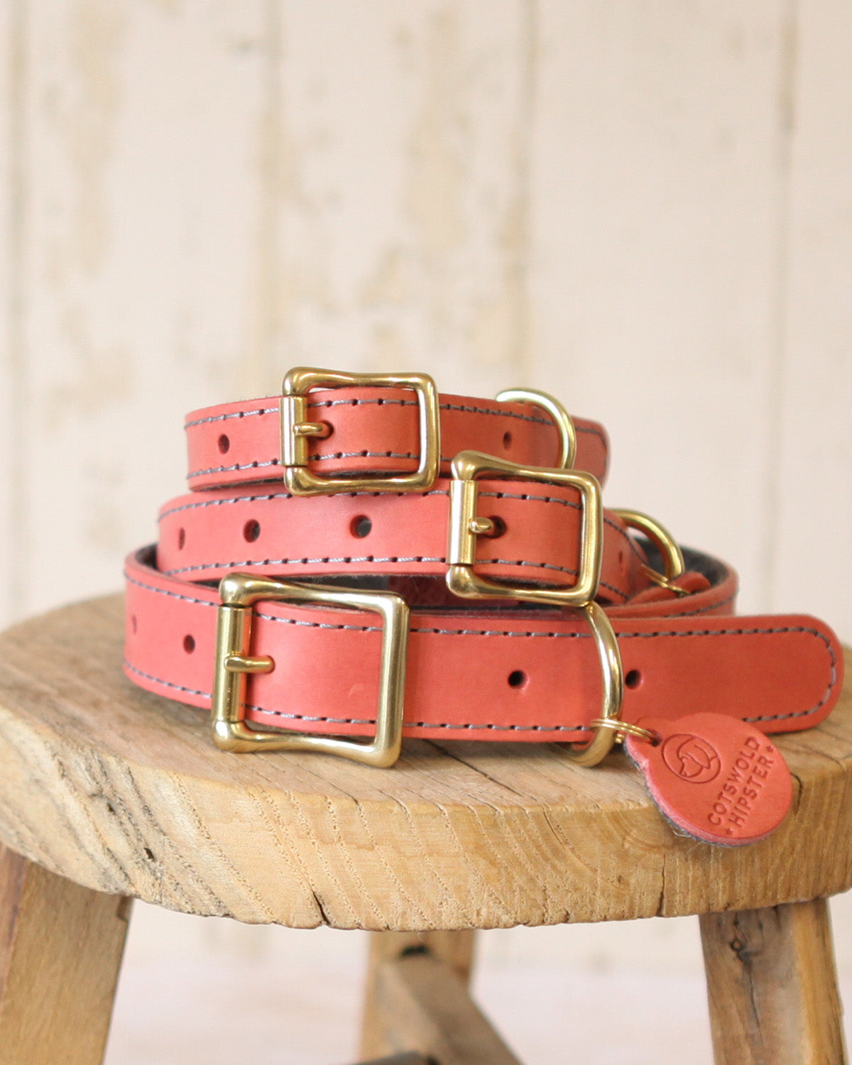 Stack of coral and charcoal limited edition dog collars showing multiple sizes from the handcrafted collection.