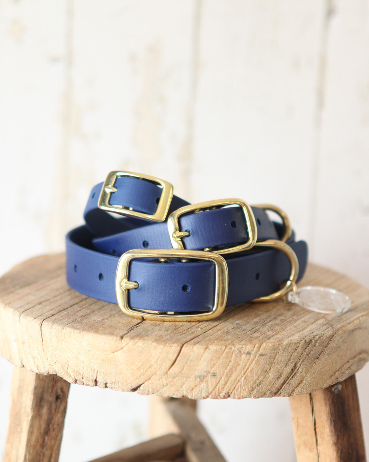 Stack of three navy BioThane® dog collars in small, medium and large sizes with solid brass hardware.