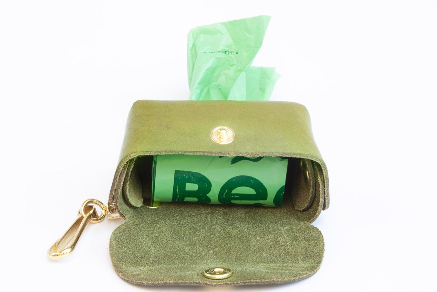 Olive Green leather poop bag holder open showing roll of bags inside, with pop stud closure, bottom dispensing hole, and brass clip for attaching, made by Cotswold Hipster