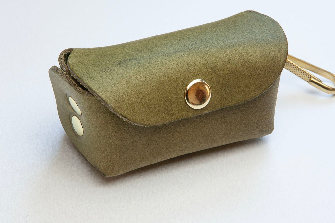Side view of Olive Green leather poop bag holder with pop stud closure, bottom dispensing hole, and brass clip for attaching, made by Cotswold Hipster