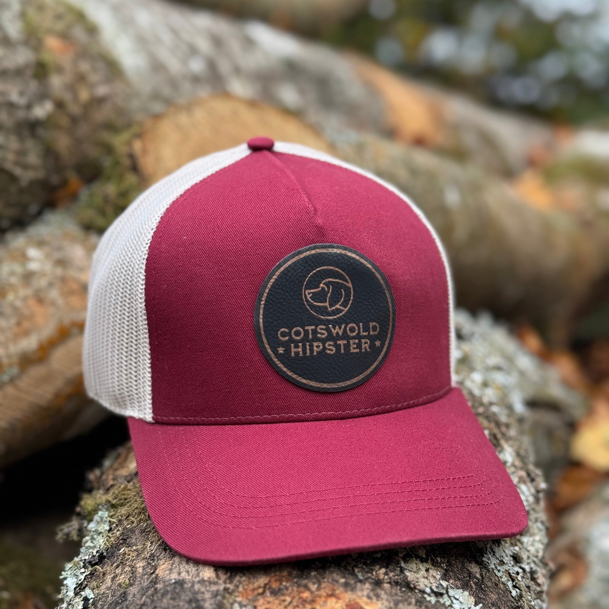 Mulberry Field Cap angled on logs in the Cotswolds, highlighting logo patch and mesh panels.