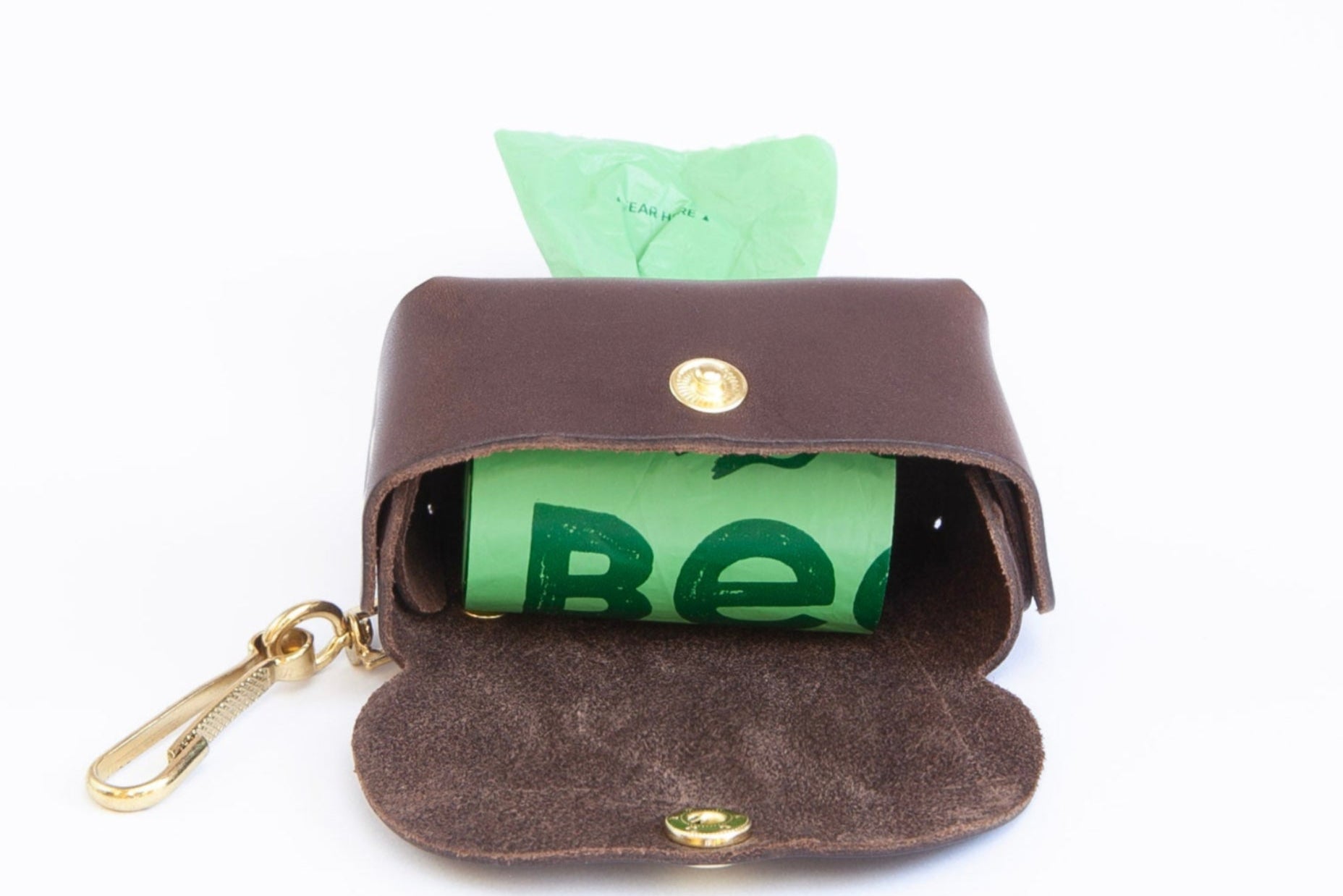 chocolate brown leather poop bag holder open showing roll of bags inside, with pop stud closure, bottom dispensing hole, and brass clip for attaching, made by Cotswold Hipster