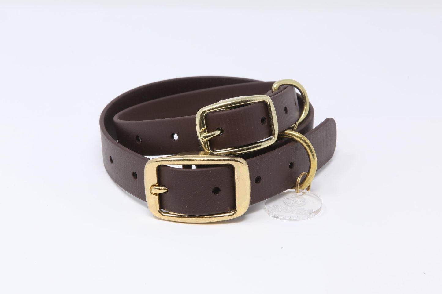 Stack of dark brown Biothane dog collars with brass hardware in multiple sizes, handmade by Cotswold Hipster 